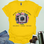 Vintage camera surrounded by flowers with the quote “When Life Gets Blurry, Adjust Your Focus.”