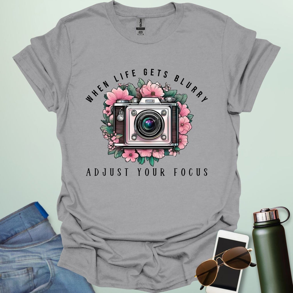 Vintage camera surrounded by flowers with the quote “When Life Gets Blurry, Adjust Your Focus.”