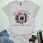 Vintage camera surrounded by flowers with the quote “When Life Gets Blurry, Adjust Your Focus.”