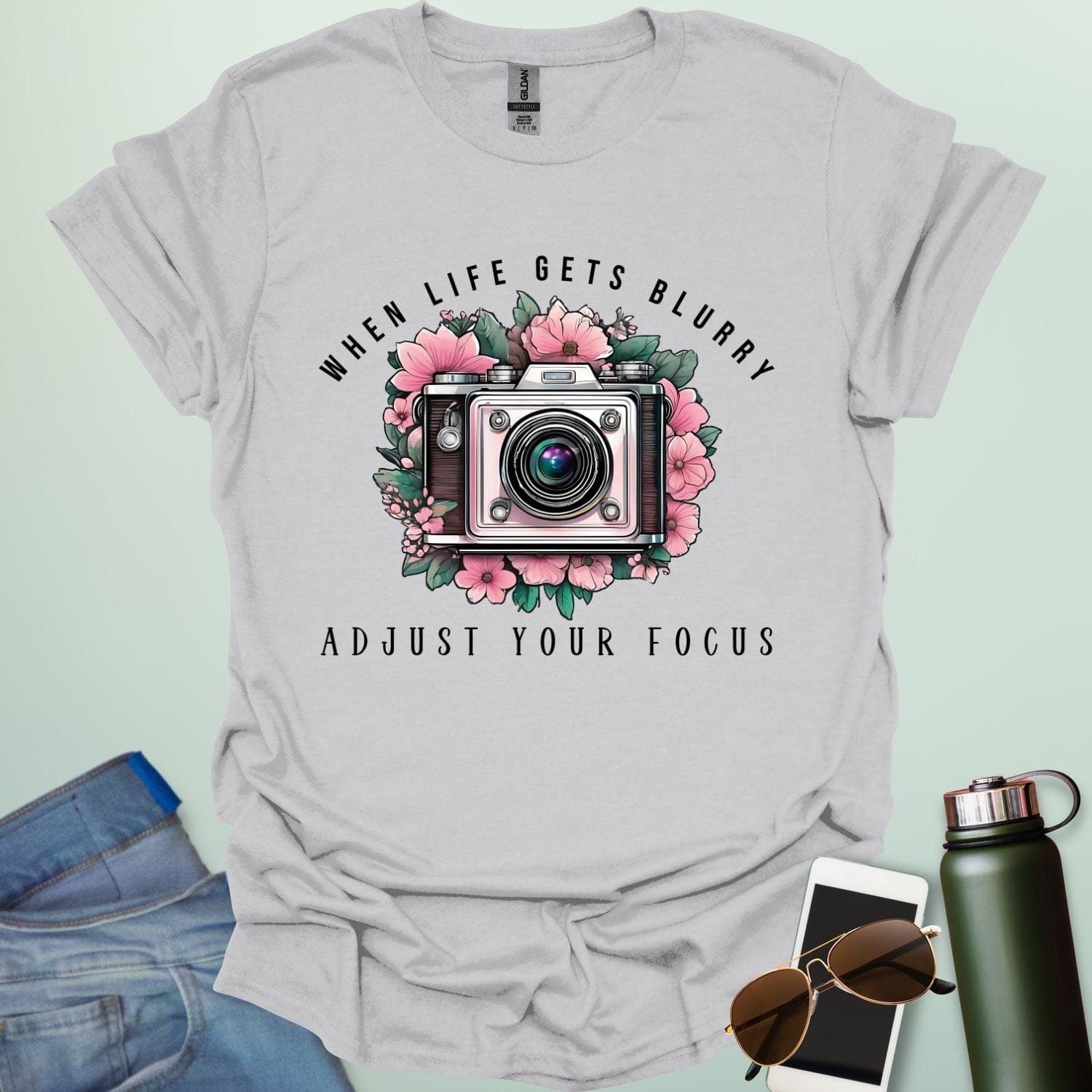 Vintage camera surrounded by flowers with the quote “When Life Gets Blurry, Adjust Your Focus.”