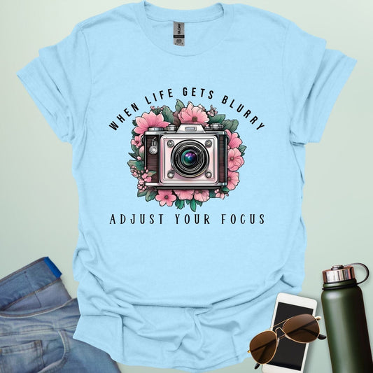 Vintage camera surrounded by flowers with the quote “When Life Gets Blurry, Adjust Your Focus.”