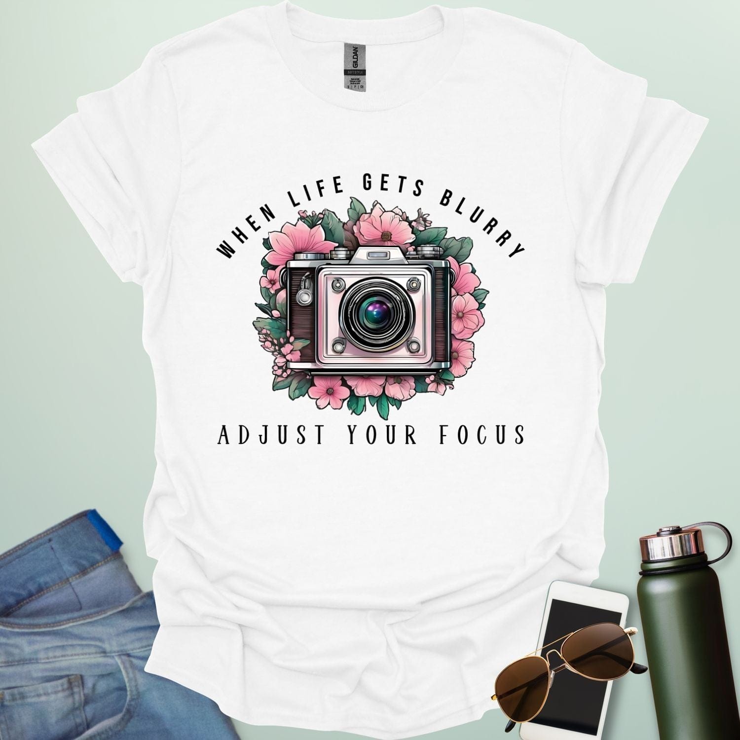 Vintage camera surrounded by flowers with the quote “When Life Gets Blurry, Adjust Your Focus.”