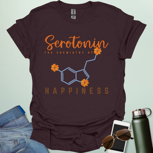 The word 'Serotonin' in cursive orange font above the text 'THE CHEMISTRY OF' in smaller orange font, above the chemical structure of serotonin in light blue with three orange flowers incorporated into the bonds. Below the chemical structure is the word 'HAPPINESS' in bold orange font.
