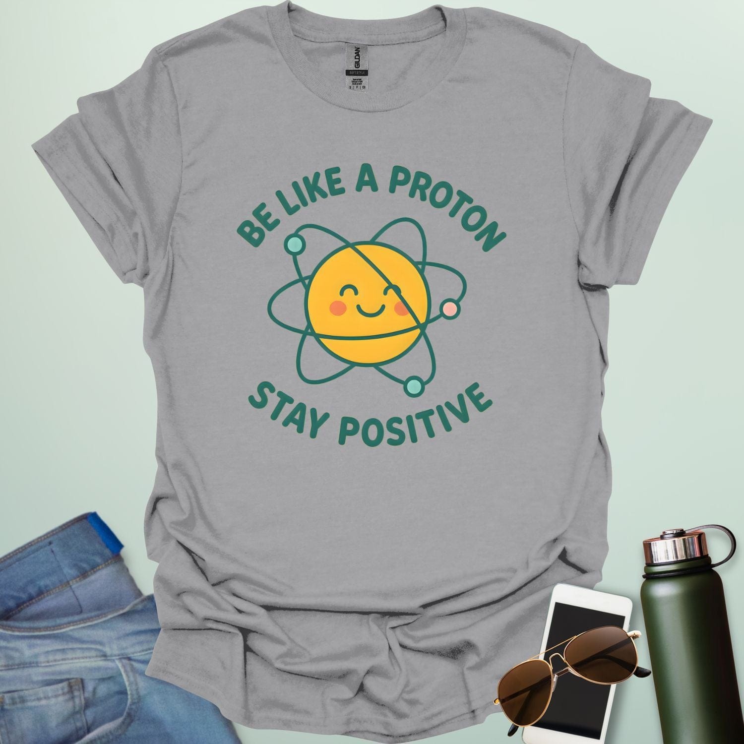 A cheerful graphic design featuring a smiling yellow proton character with orbiting electrons and the text "BE LIKE A PROTON STAY POSITIVE."