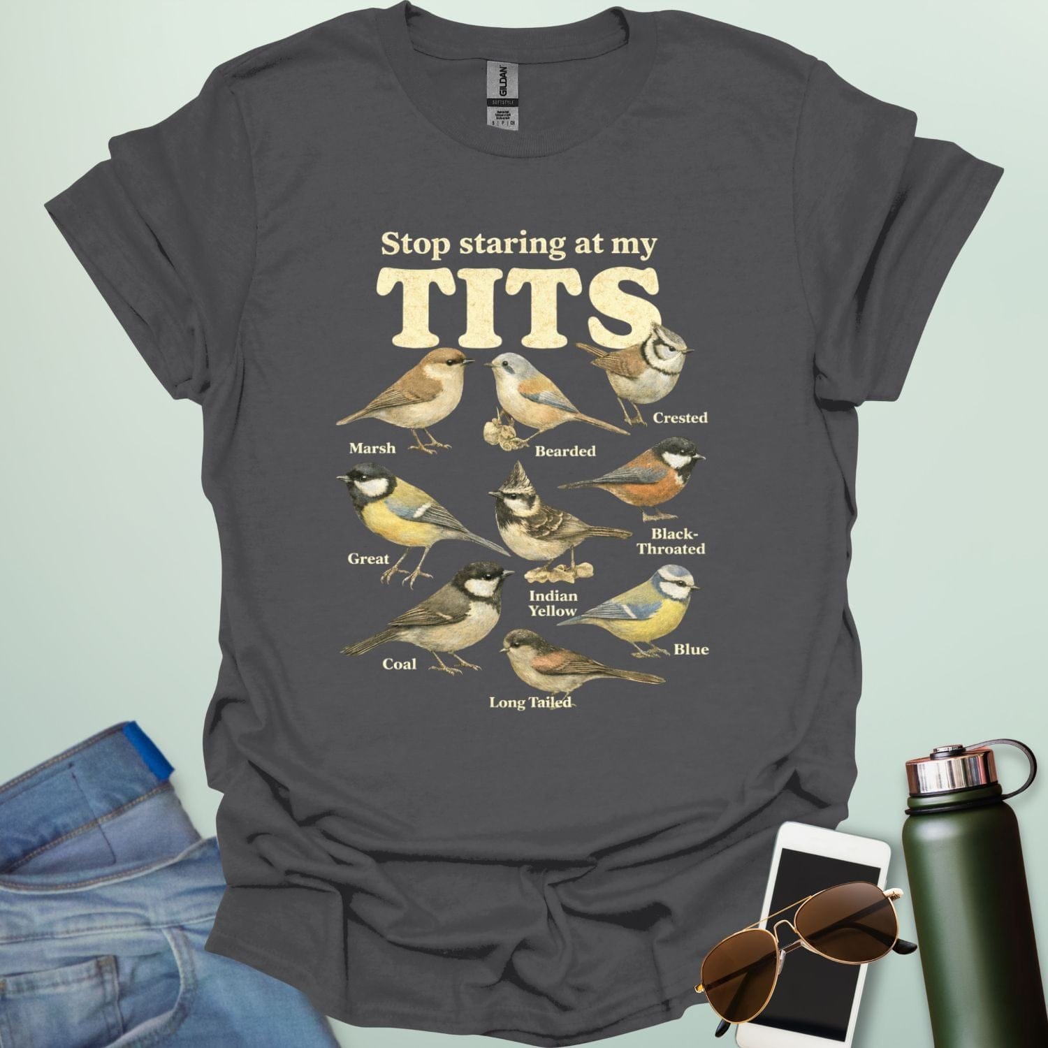 A t-shirt featuring the text "Stop staring at my TITS" above nine vintage-style illustrations of different tit bird species, including the Bearded, Crested, and Long Tailed tits.