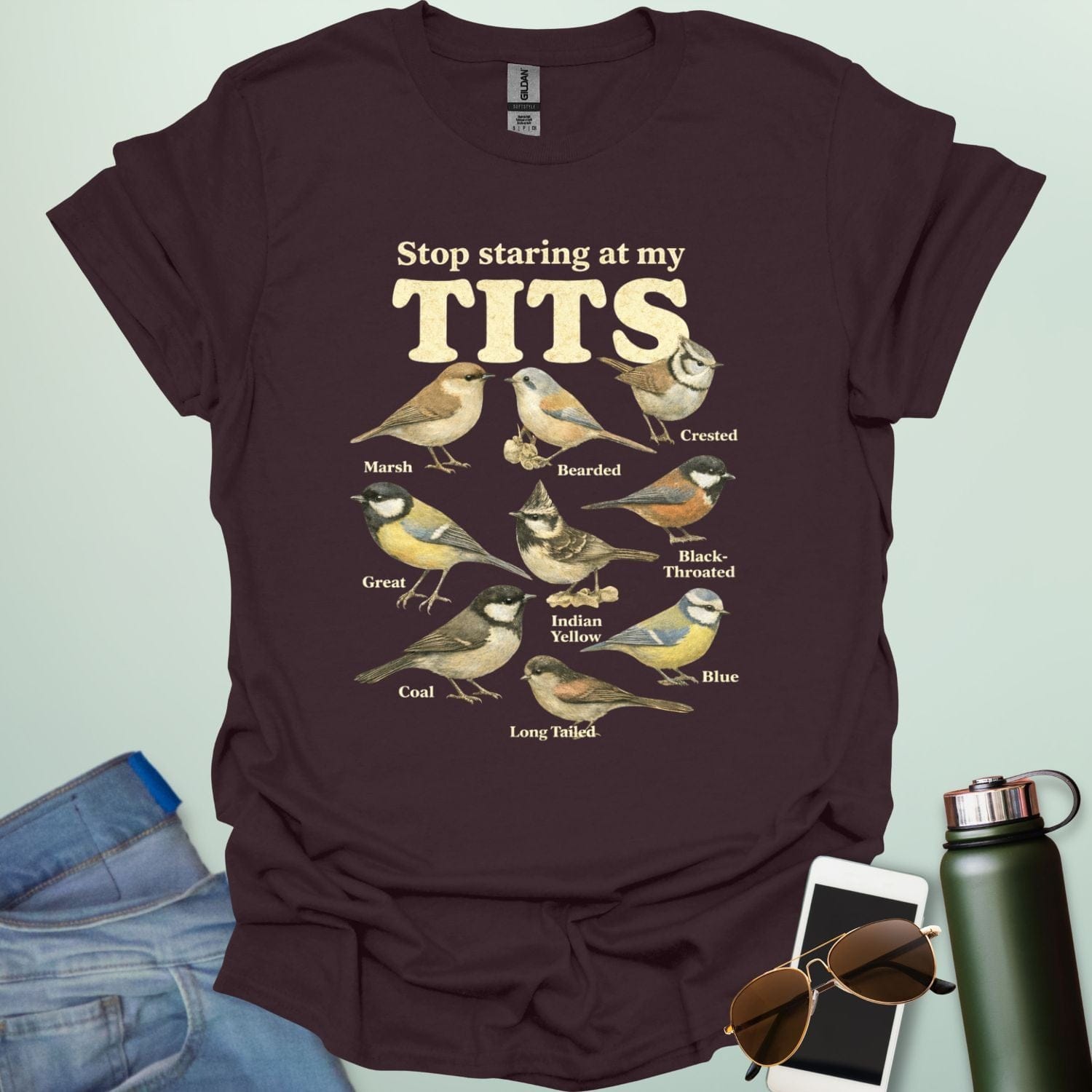 A t-shirt featuring the text "Stop staring at my TITS" above nine vintage-style illustrations of different tit bird species, including the Bearded, Crested, and Long Tailed tits.