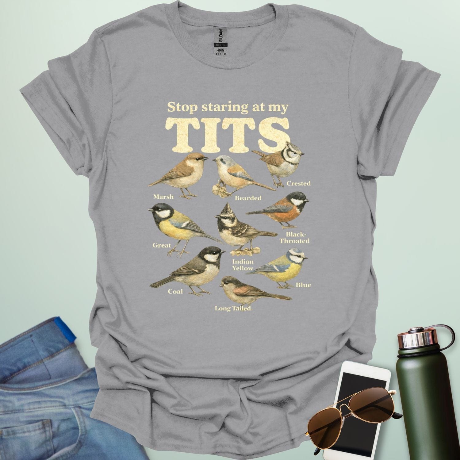 A t-shirt featuring the text "Stop staring at my TITS" above nine vintage-style illustrations of different tit bird species, including the Bearded, Crested, and Long Tailed tits.