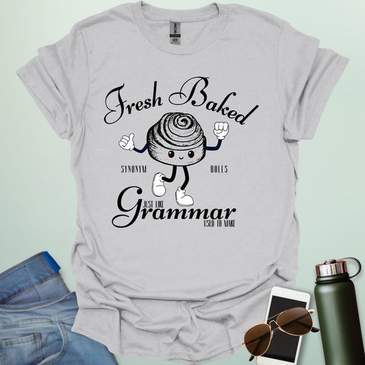 A funny t-shirt with a cute cartoon cinnamon roll and the text 'Fresh Baked Synonym Rolls Just Like Grammar Used to Make.'
