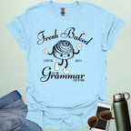 A funny t-shirt with a cute cartoon cinnamon roll and the text 'Fresh Baked Synonym Rolls Just Like Grammar Used to Make.'