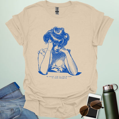 A tan shirt with blue line art illustration of a woman looking frustrated with her head in her hands, above the text 'My social life is like my code:' and 'It needs debugging.
