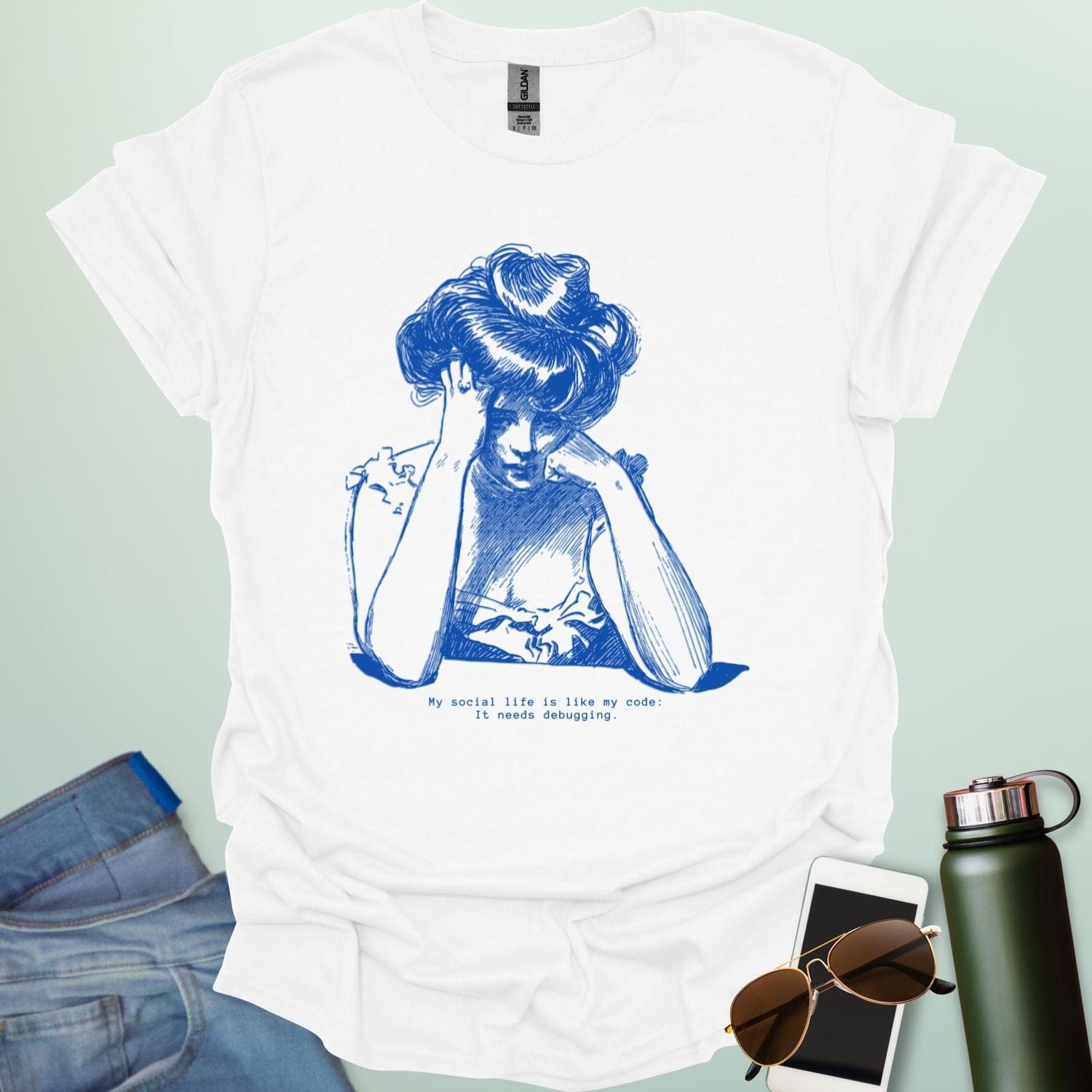 A white shirt with blue line art illustration of a woman looking frustrated with her head in her hands, above the text 'My social life is like my code:' and 'It needs debugging.