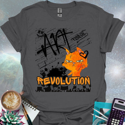The word 'ART' in a bold, black graffiti style above an orange cartoon cat with a determined expression and a heart graphic. Below is the word 'REVOLUTION' in orange outlined in black, above a silhouette of a crowd holding signs.