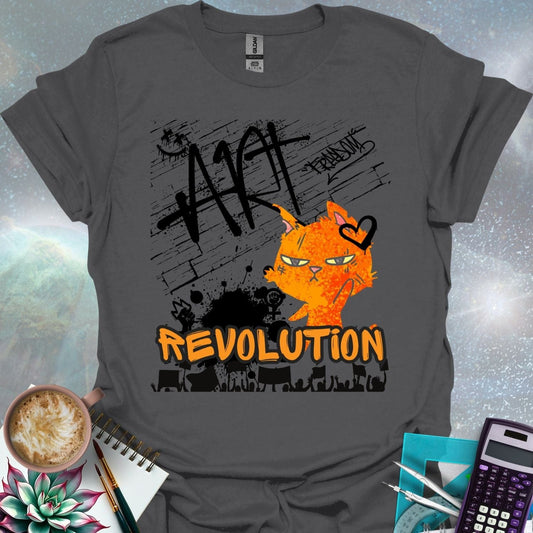 The word 'ART' in a bold, black graffiti style above an orange cartoon cat with a determined expression and a heart graphic. Below is the word 'REVOLUTION' in orange outlined in black, above a silhouette of a crowd holding signs.