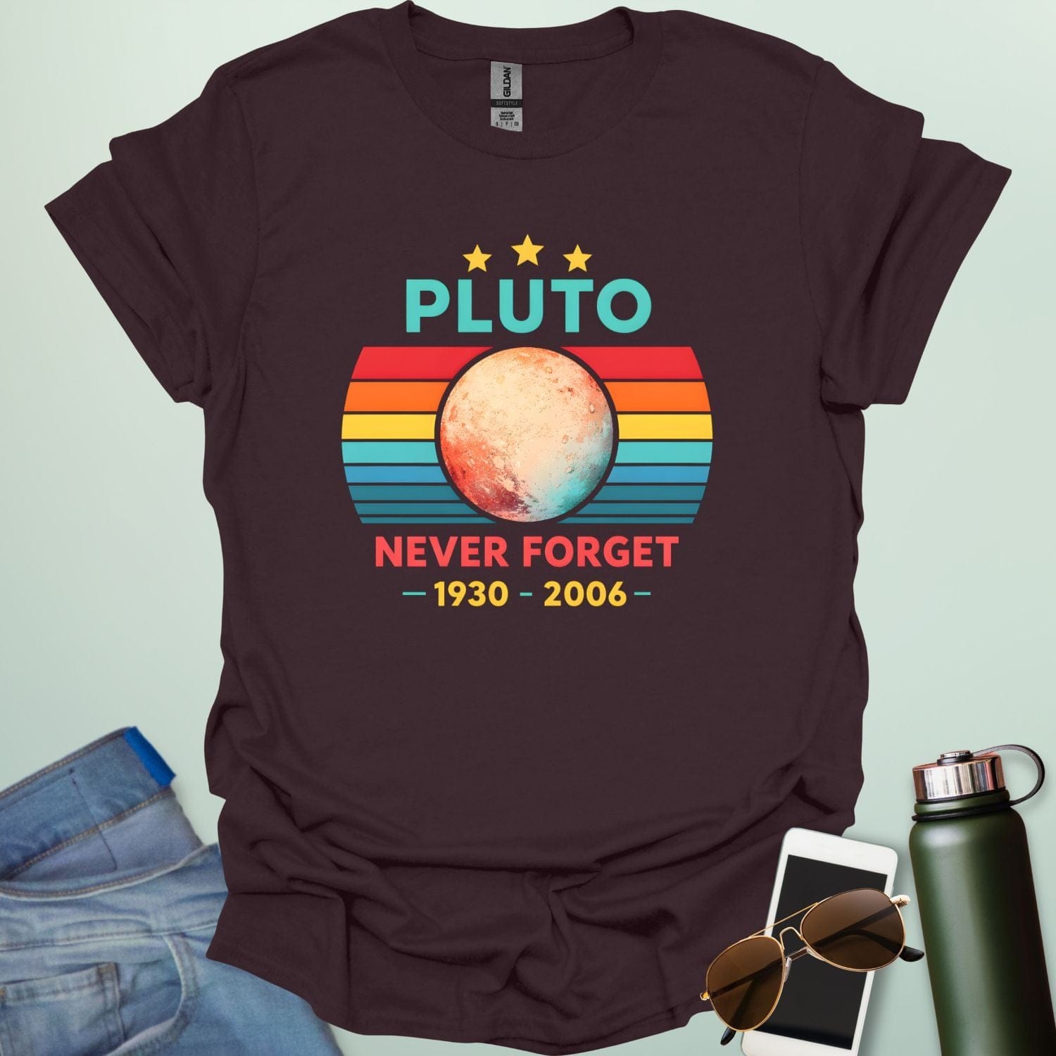 A retro-style graphic featuring the planet Pluto in front of a striped sunset background with the text "PLUTO NEVER FORGET — 1930 - 2006 —".