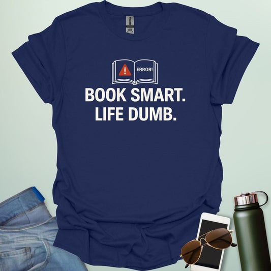 A minimalist graphic design featuring an open book with a red warning triangle and the word "ERROR!" above the bold text "BOOK SMART. LIFE DUMB."