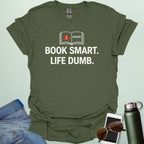 A minimalist graphic design featuring an open book with a red warning triangle and the word "ERROR!" above the bold text "BOOK SMART. LIFE DUMB."