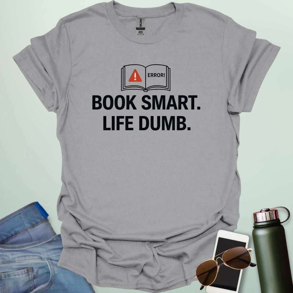 A minimalist graphic design featuring an open book with a red warning triangle and the word "ERROR!" above the bold text "BOOK SMART. LIFE DUMB."