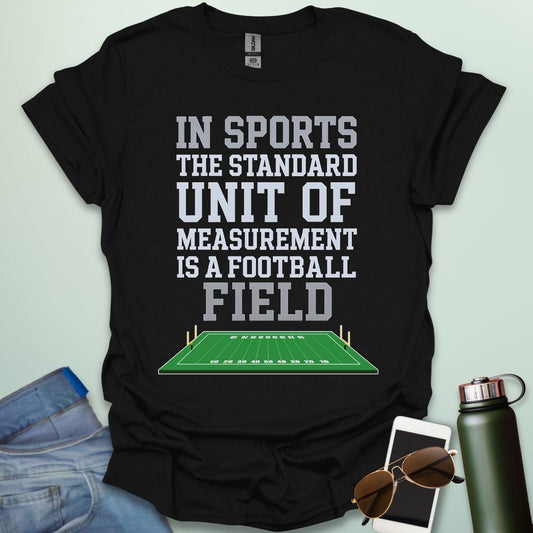 A black t-shirt with the text 'IN SPORTS THE STANDARD UNIT OF MEASUREMENT IS A FOOTBALL FIELD' above an illustration of a football field.