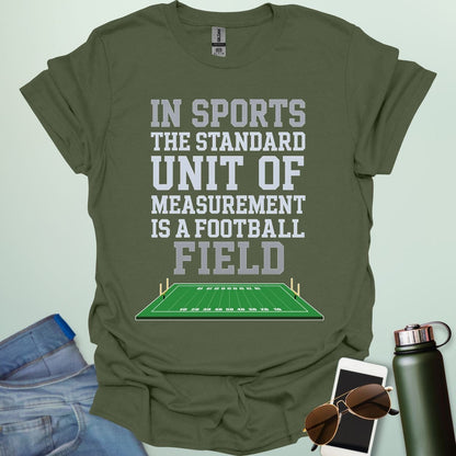 A military green t-shirt with the text 'IN SPORTS THE STANDARD UNIT OF MEASUREMENT IS A FOOTBALL FIELD' above an illustration of a football field.