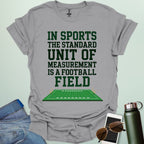 A sport grey t-shirt with the text 'IN SPORTS THE STANDARD UNIT OF MEASUREMENT IS A FOOTBALL FIELD' above an illustration of a football field.