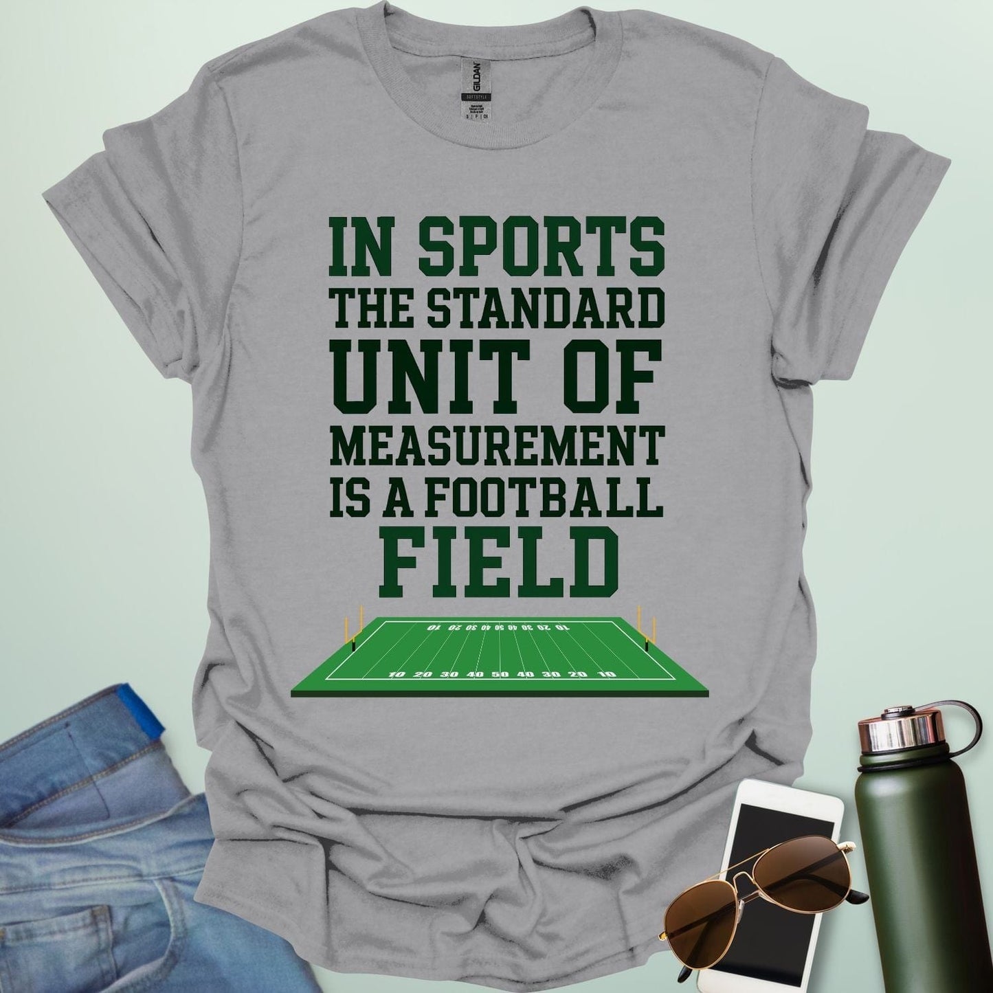 A sport grey t-shirt with the text 'IN SPORTS THE STANDARD UNIT OF MEASUREMENT IS A FOOTBALL FIELD' above an illustration of a football field.