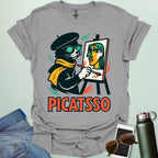 A sport grey t-shirt with a cartoon of a cat painting a Picasso-style portrait on an easel and the text 'PICATSSO' below.
