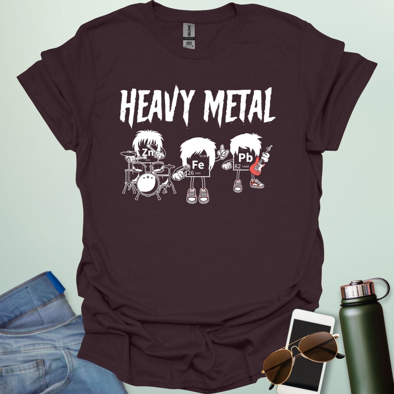 A dark chocolate t-shirt with a cartoon graphic of three chemical elements—Zn, Fe, and Pb—dressed as a heavy metal rock band with the text 'HEAVY METAL' above them.