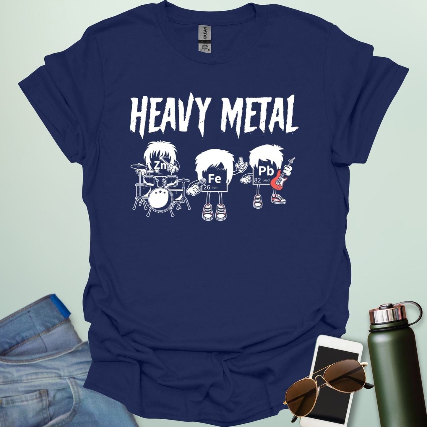 A navy blue t-shirt with a cartoon graphic of three chemical elements—Zn, Fe, and Pb—dressed as a heavy metal rock band with the text 'HEAVY METAL' above them.