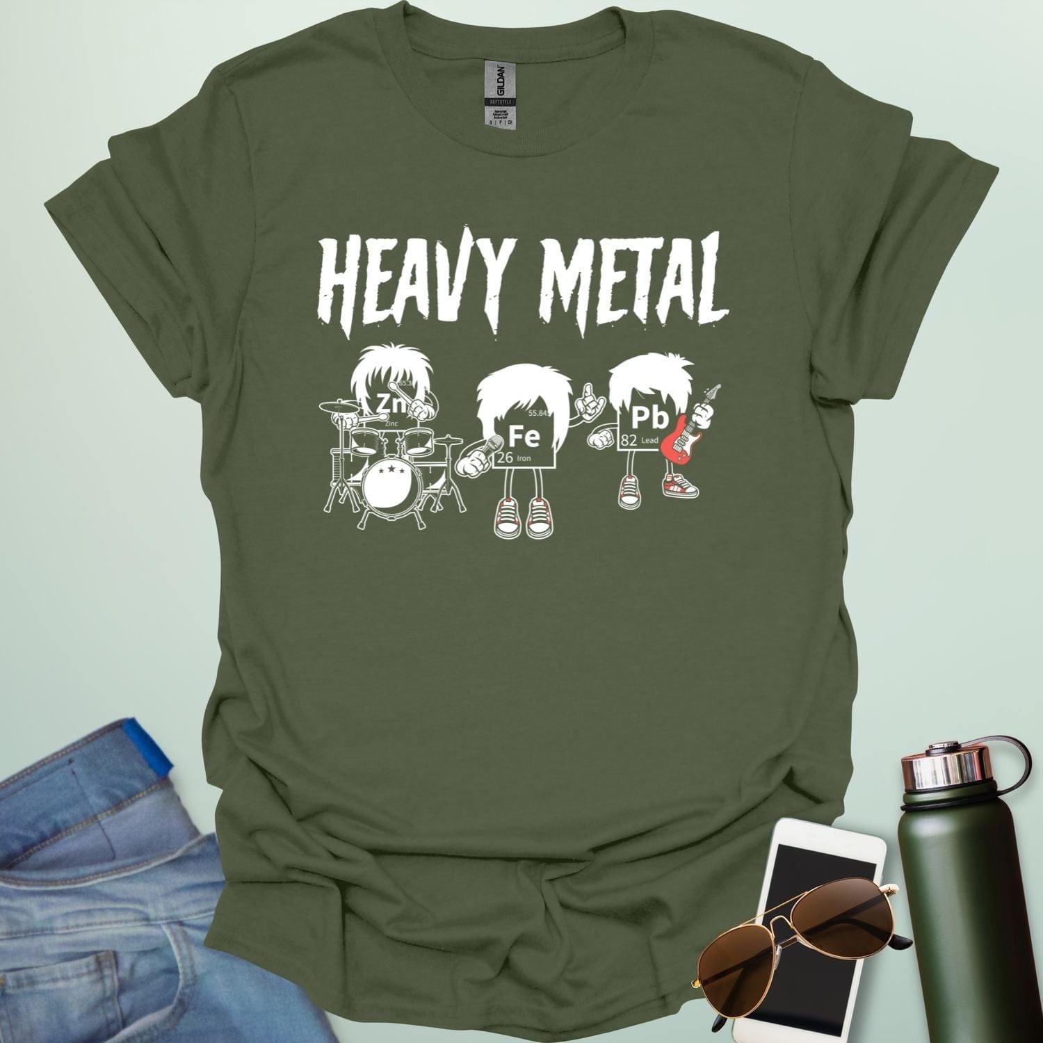 A military green t-shirt with a cartoon graphic of three chemical elements—Zn, Fe, and Pb—dressed as a heavy metal rock band with the text 'HEAVY METAL' above them.