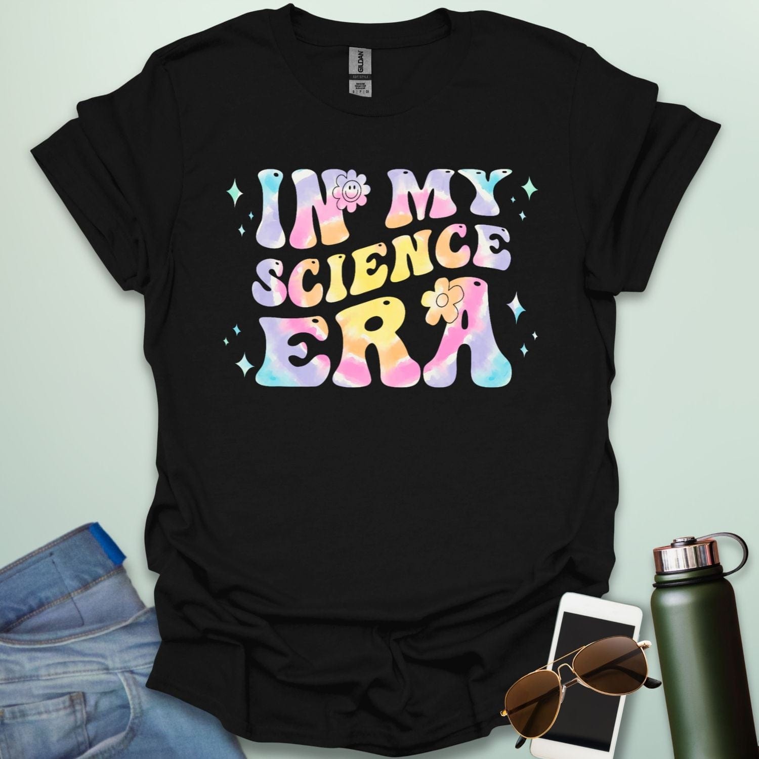 A black t-shirt with wavy, tie-dye text that says 'IN MY SCIENCE ERA' with flowers and stars.