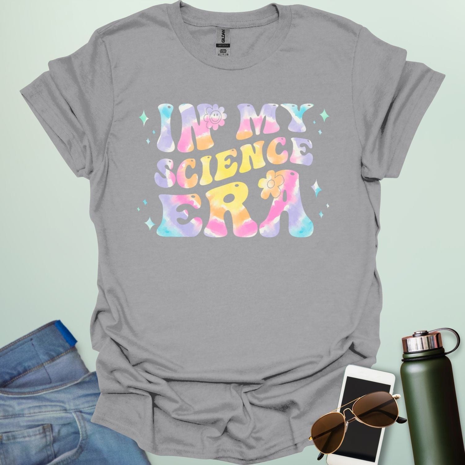 A sport grey t-shirt with wavy, tie-dye text that says 'IN MY SCIENCE ERA' with flowers and stars.
