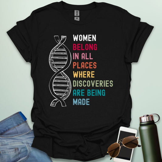 A black t-shirt with the text 'WOMEN BELONG IN ALL PLACES WHERE DISCOVERIES ARE BEING MADE' in a typewriter-style font.