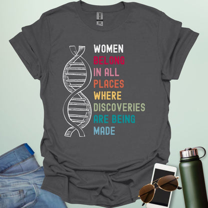 A charcoal grey t-shirt with the text 'WOMEN BELONG IN ALL PLACES WHERE DISCOVERIES ARE BEING MADE' in a typewriter-style font.