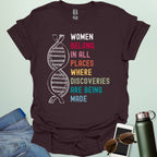 A dark chocolate t-shirt with the text 'WOMEN BELONG IN ALL PLACES WHERE DISCOVERIES ARE BEING MADE' in a typewriter-style font.