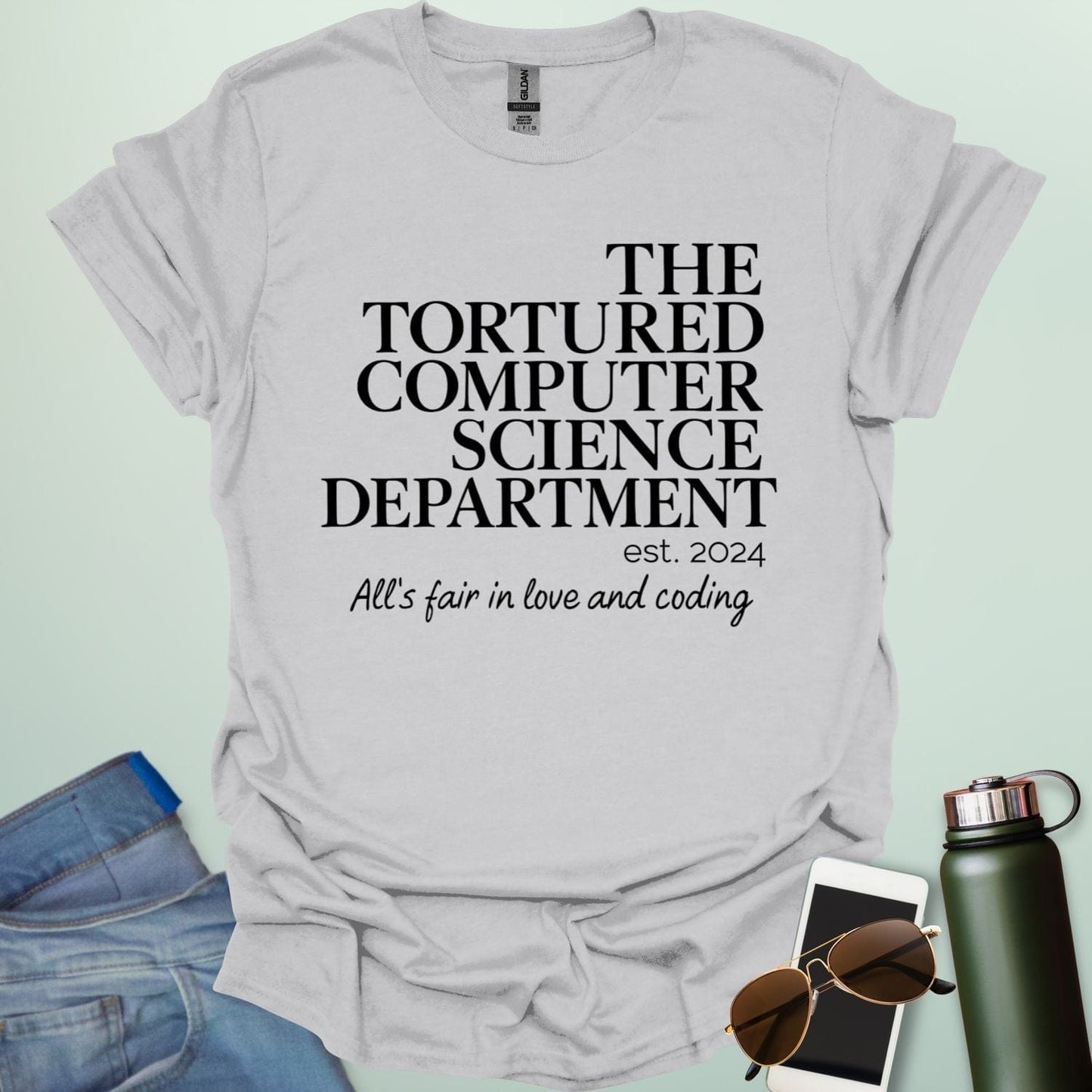 An ice grey t-shirt with the text 'THE TORTURED COMPUTER SCIENCE DEPARTMENT est. 2024' and 'All's fair in love and coding.'