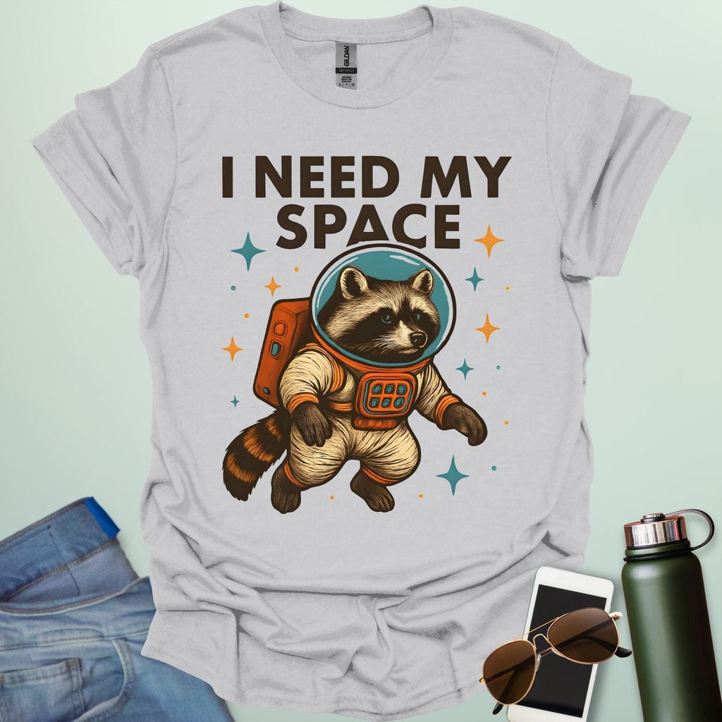 An ice grey t-shirt with a cartoon illustration of a raccoon in an astronaut suit and the text 'I NEED MY SPACE.'