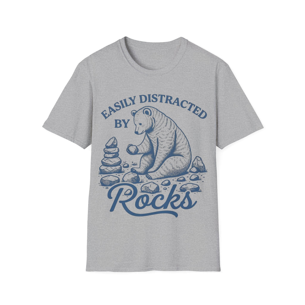 Linocut-style illustration of a bear sitting down examining a stone beside a cairn stack, framed by text reading 'EASILY DISTRACTED BY ROCKS'.