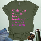 A military green t-shirt with the text 'Girls just wanna have funding for scientific research' in a pink serif font.
