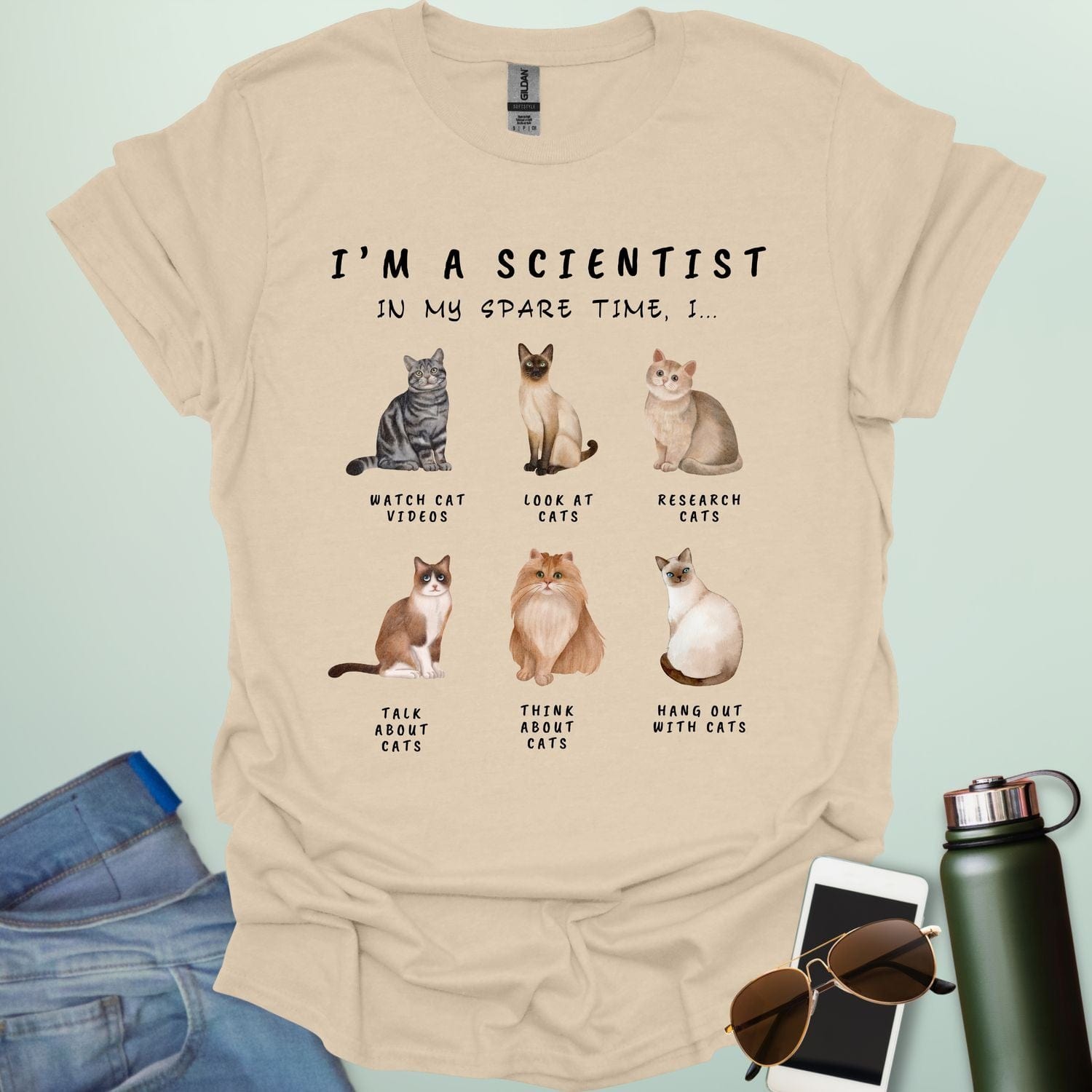 Sand t-shirt with cat-themed text and illustrations on a light blue background