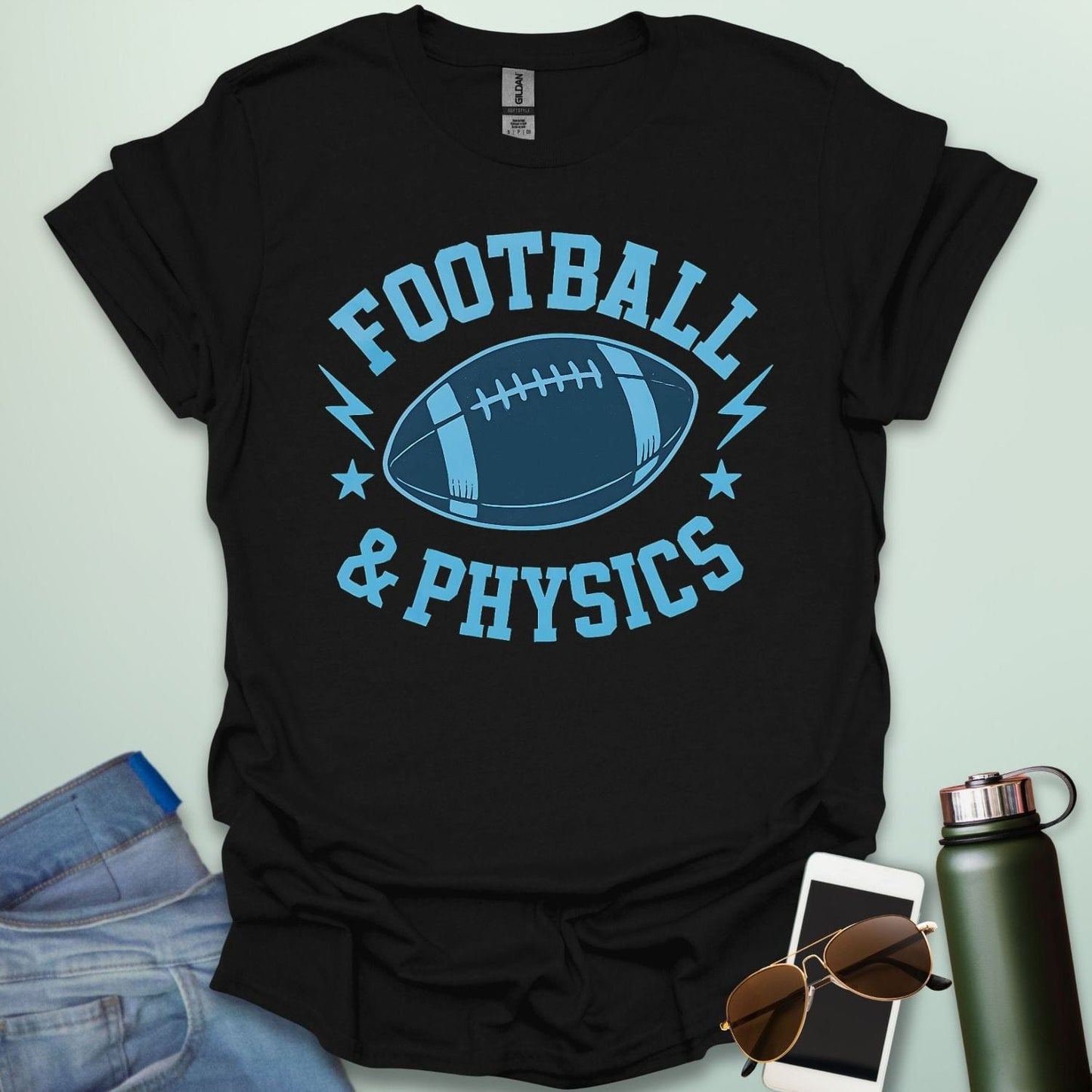 A black t-shirt with a dynamic illustration of a football surrounded by lightning bolts and stars, with the text 'FOOTBALL & PHYSICS.'