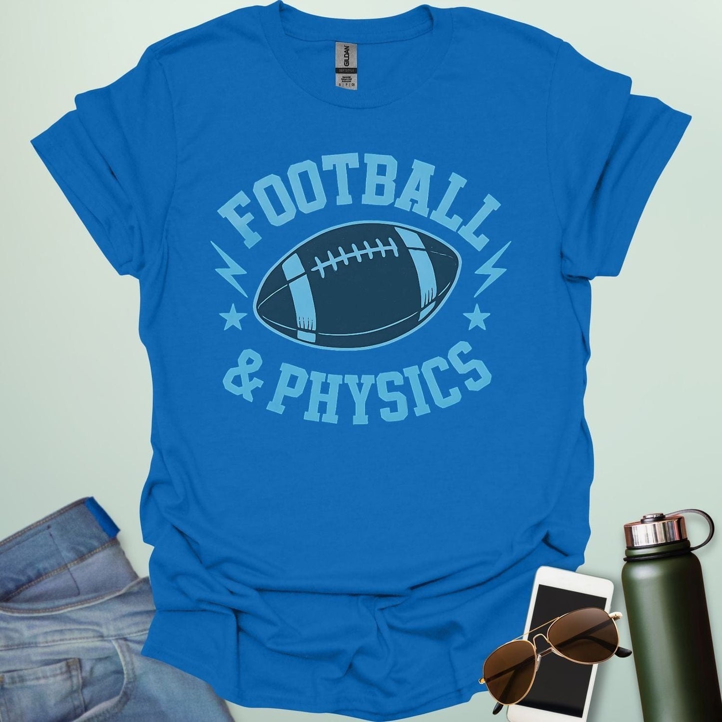 A royal blue t-shirt with a dynamic illustration of a football surrounded by lightning bolts and stars, with the text 'FOOTBALL & PHYSICS.'