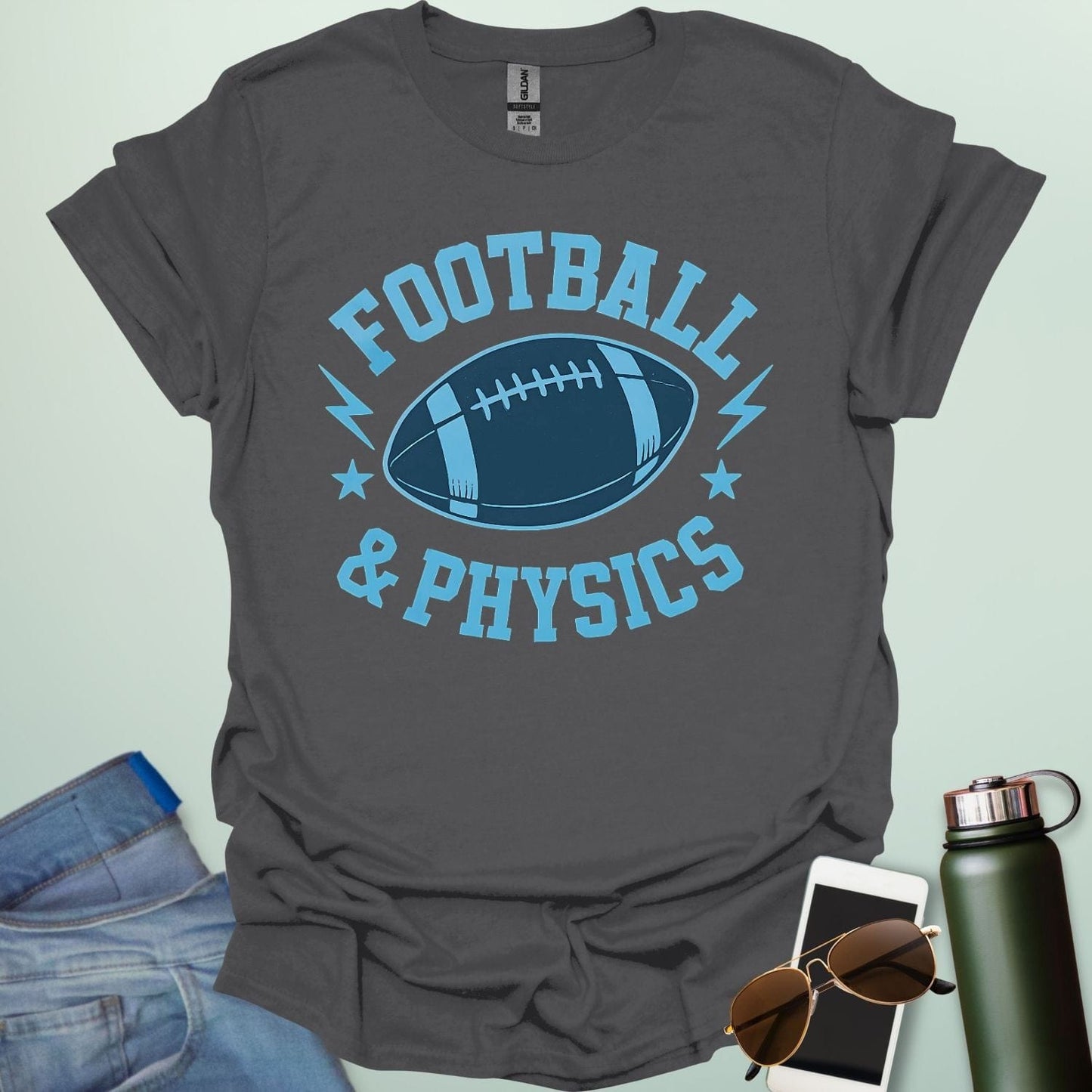 A charcoal grey t-shirt with a dynamic illustration of a football surrounded by lightning bolts and stars, with the text 'FOOTBALL & PHYSICS.'