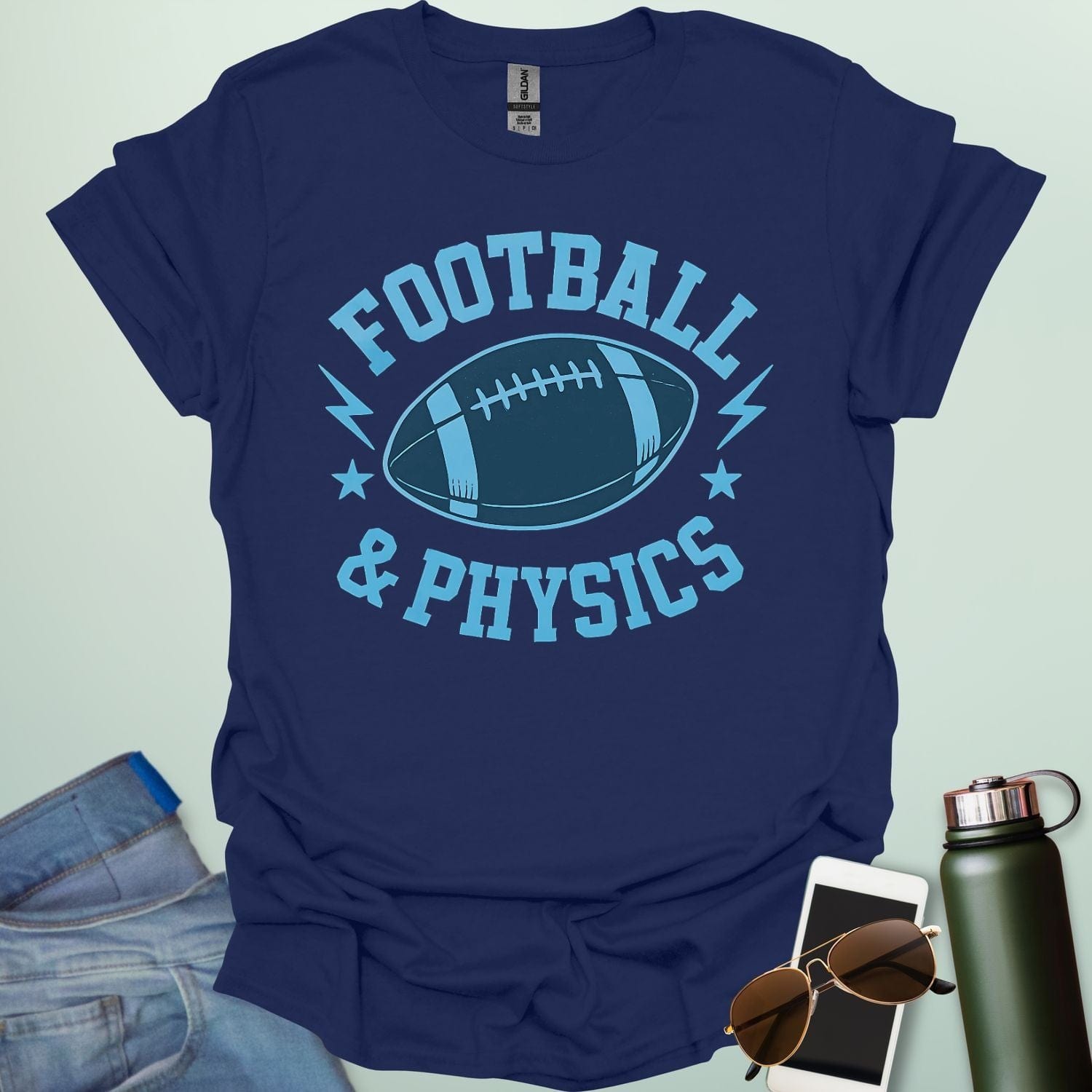 A navy blue t-shirt with a dynamic illustration of a football surrounded by lightning bolts and stars, with the text 'FOOTBALL & PHYSICS.'