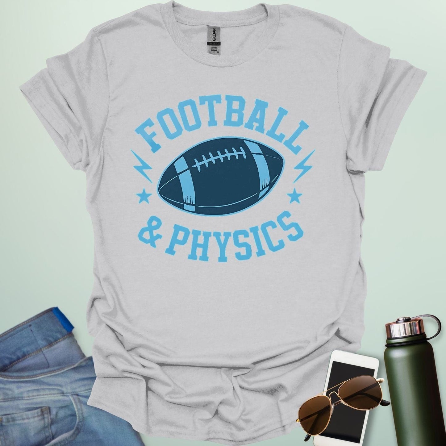 A ice grey t-shirt with a dynamic illustration of a football surrounded by lightning bolts and stars, with the text 'FOOTBALL & PHYSICS.'