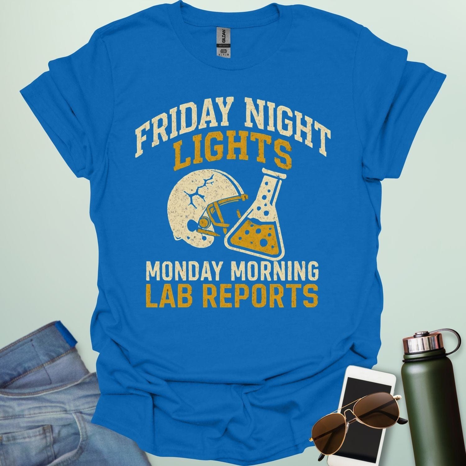 A royal blue t-shirt with a vintage football helmet and a cracked lab flask, with the text 'FRIDAY NIGHT LIGHTS' and 'MONDAY MORNING LAB REPORTS.'