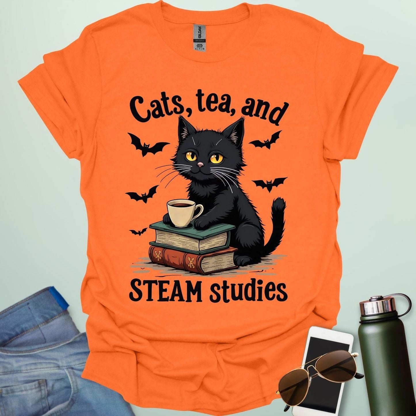 Cats, Tea, and STEAM Studies t-shirt with black cat, books, tea cup, and bats — a cozy geeky design for STEM/STEAM fans and book lovers.