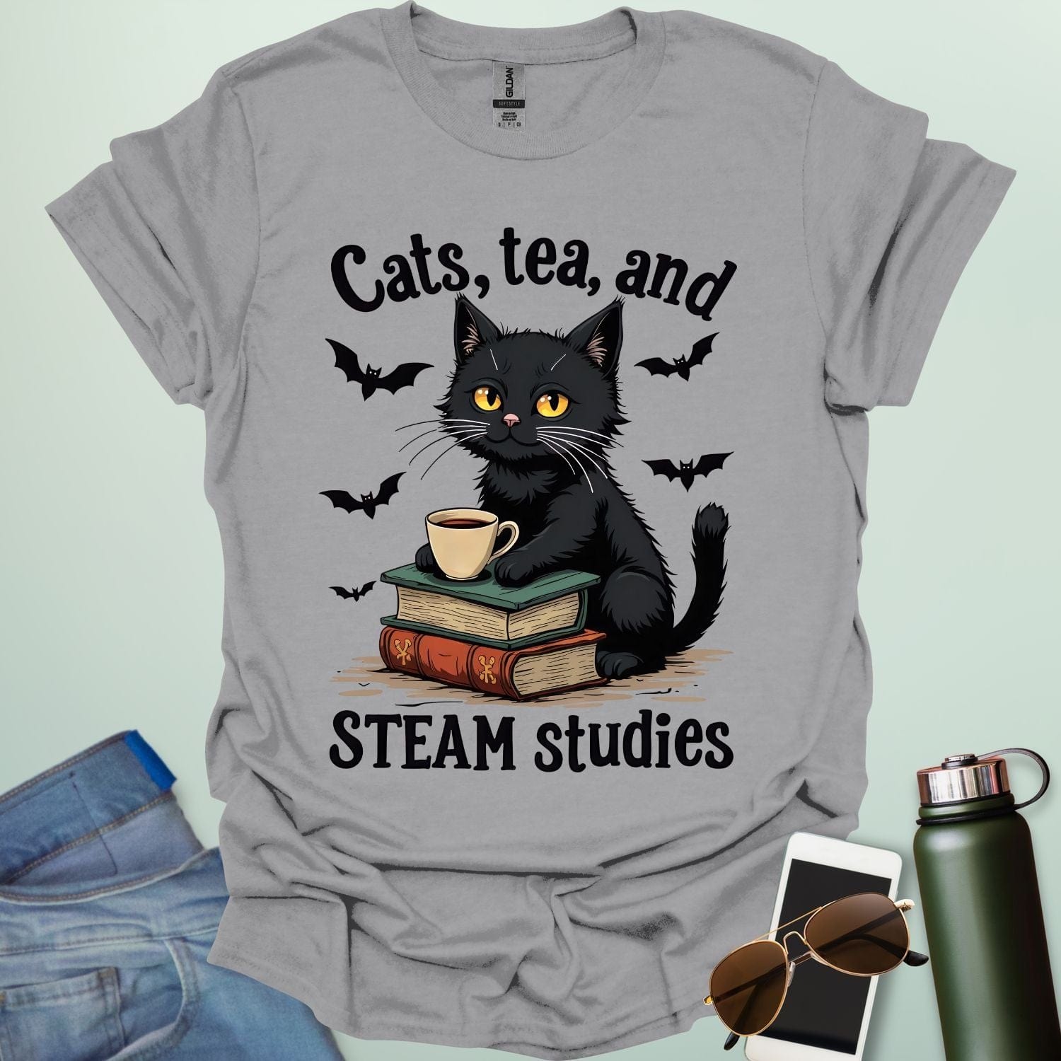Cats, Tea, and STEAM Studies t-shirt with black cat, books, tea cup, and bats — a cozy geeky design for STEM/STEAM fans and book lovers.