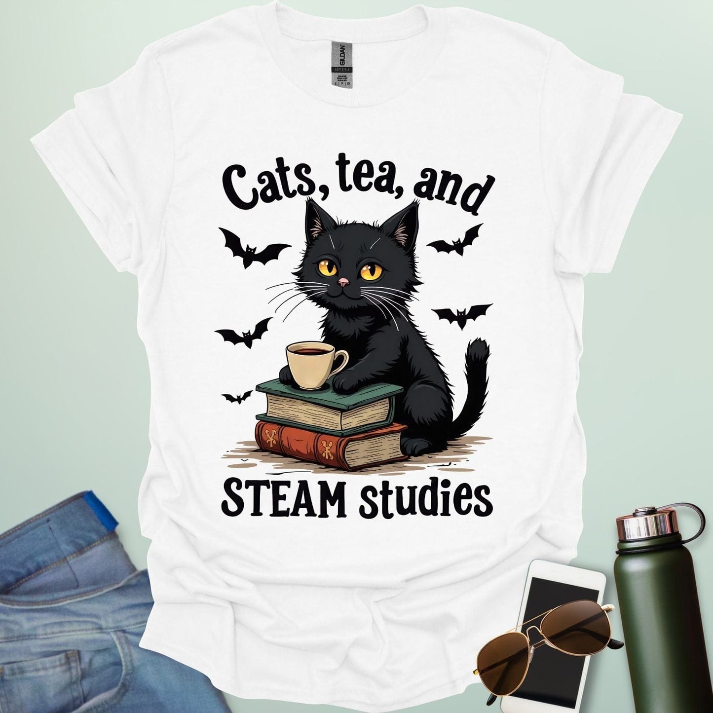 Cats, Tea, and STEAM Studies t-shirt with black cat, books, tea cup, and bats — a cozy geeky design for STEM/STEAM fans and book lovers.
